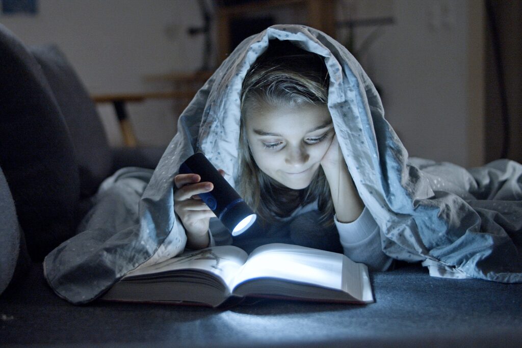 Girl reading with a torch light